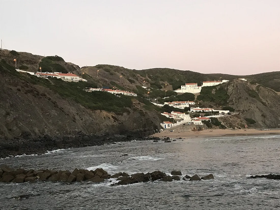 De surfbaai Praia da Arrifana onder de kliffen bij Aljezur met het dorp op de rand