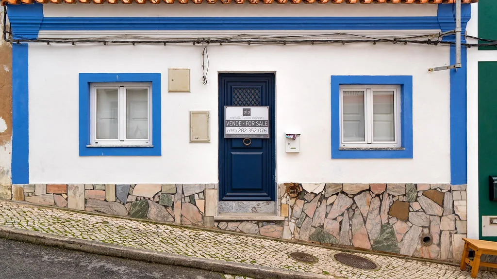 Een traditioneel wit huis met blauwe omlijsting en calçada in de oude kern van Alvor