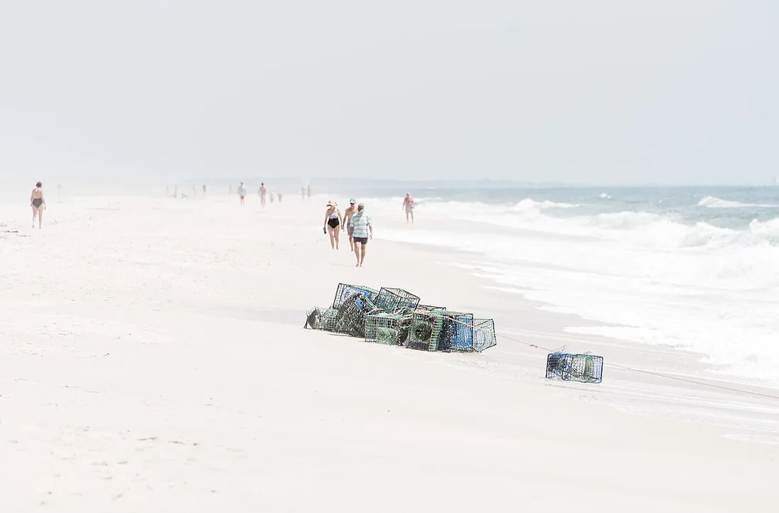 Wandelaars op het brede, lege strand van Praia do Barril met aangespoelde octopuskorven