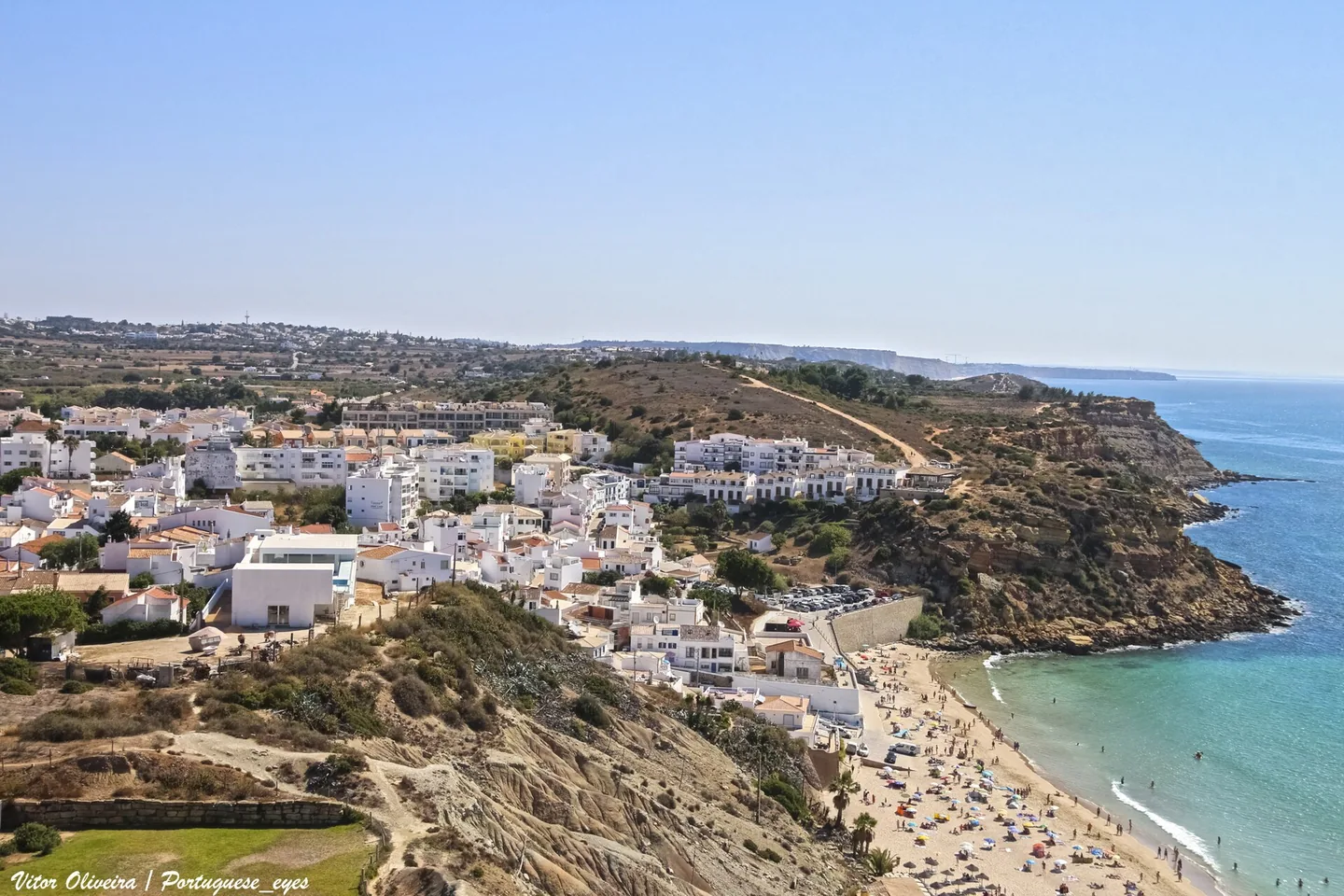 De witte huizen van Burgau op de helling boven het strand, gezien vanaf het kustpad