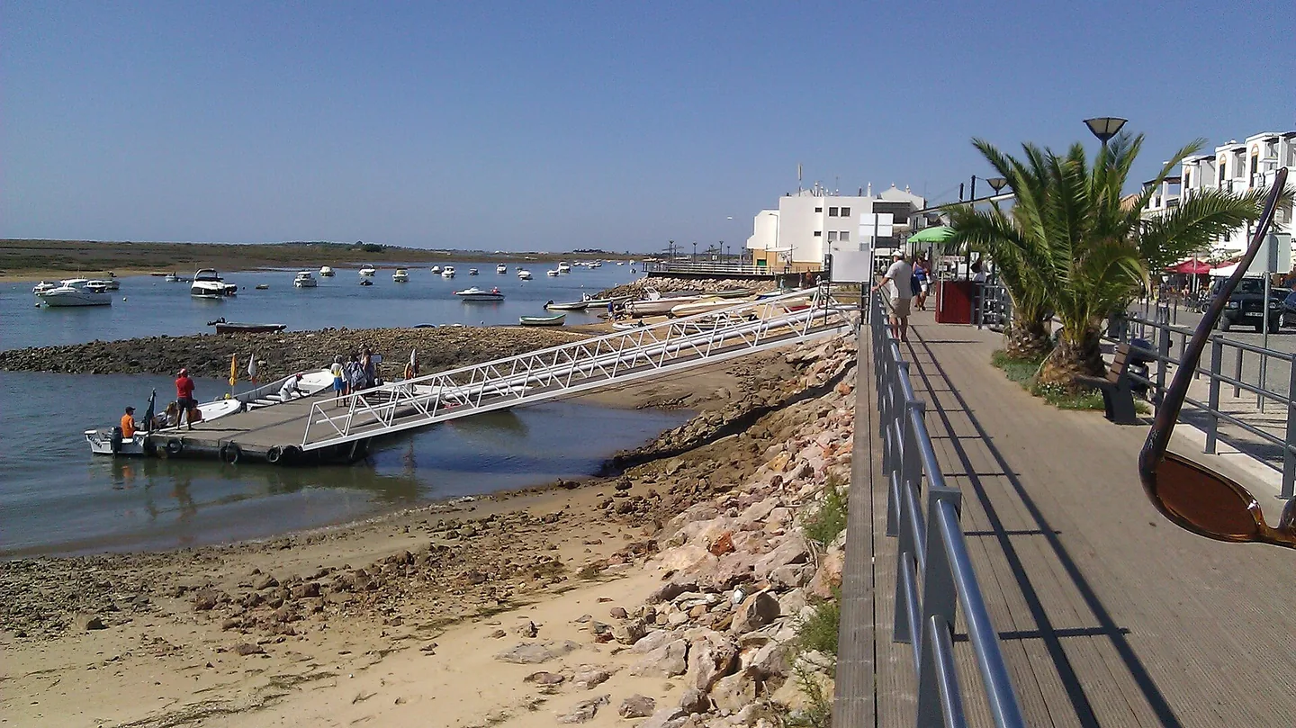 De vlakke houten boardwalk langs de lagune bij Cabanas de Tavira
