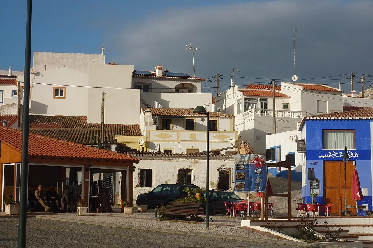 Het dorpsplein van Carrapateira met witte huizen en een terras aan de Costa Vicentina