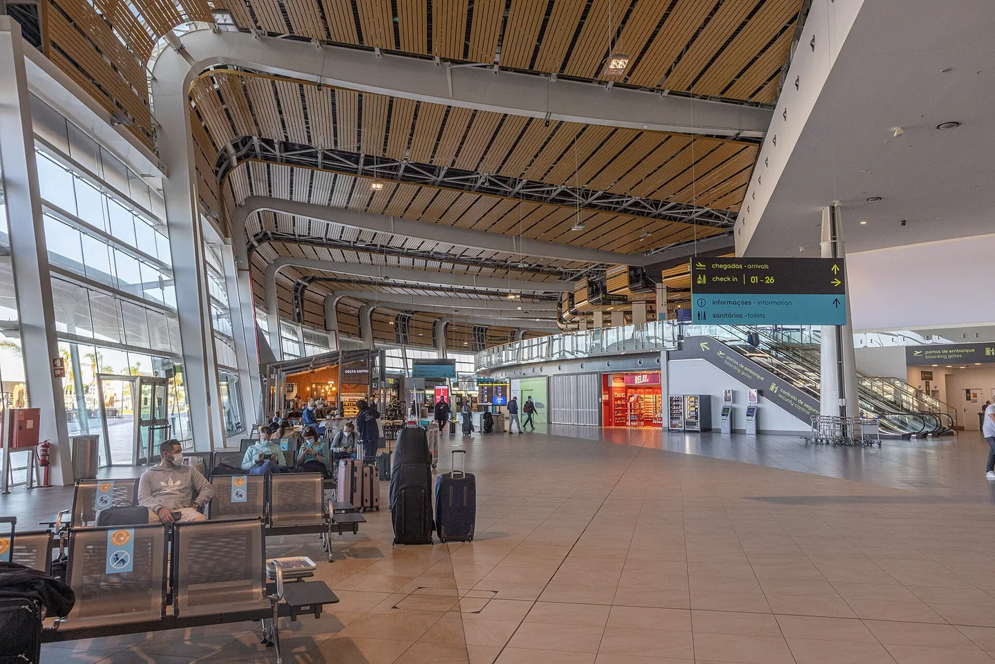 De vertrekhal van Faro Airport met houten plafond, wachtende reizigers en koffers
