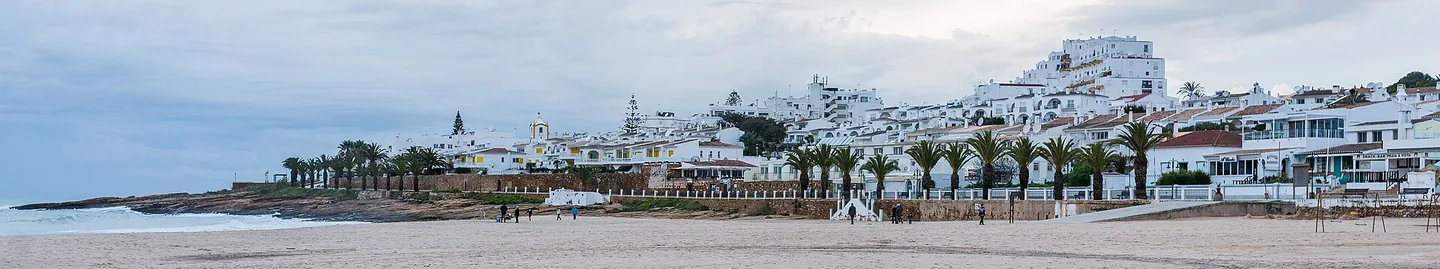 Het strand van Praia da Luz met de zwarte Rocha Negra-rots