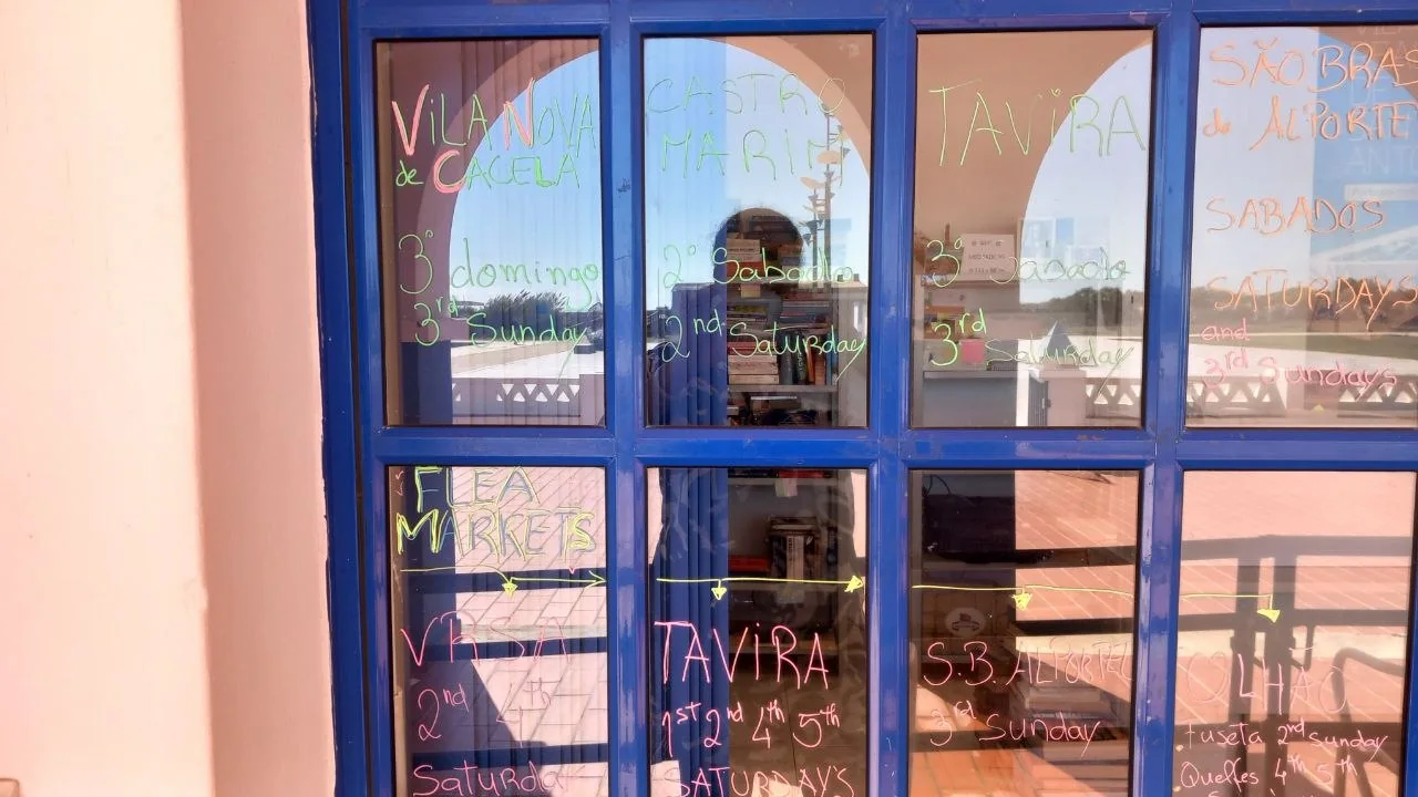 Het raam van het informatiekantoor in Manta Rota, met de markt- en vlooienmarktdagen van de oostelijke Algarve met stift op de blauwe ruiten geschreven