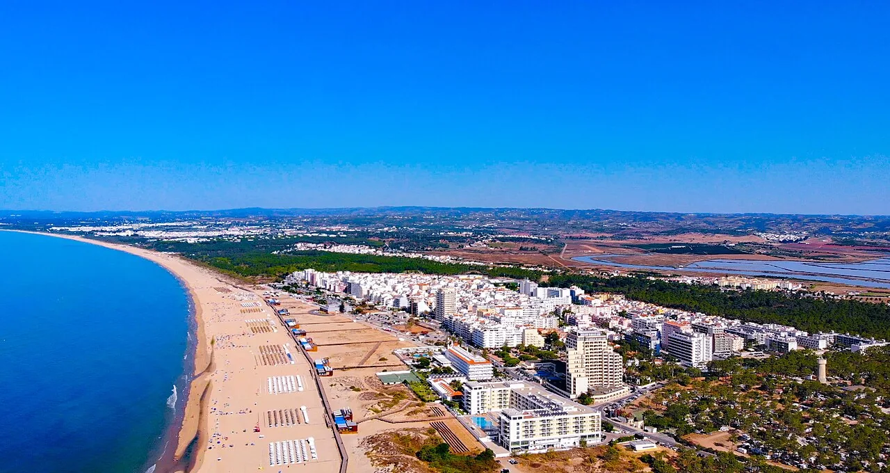Luchtfoto van Monte Gordo: de witte badplaats langs een breed strand dat kilometers doorloopt, met dennenbos en achterland erachter