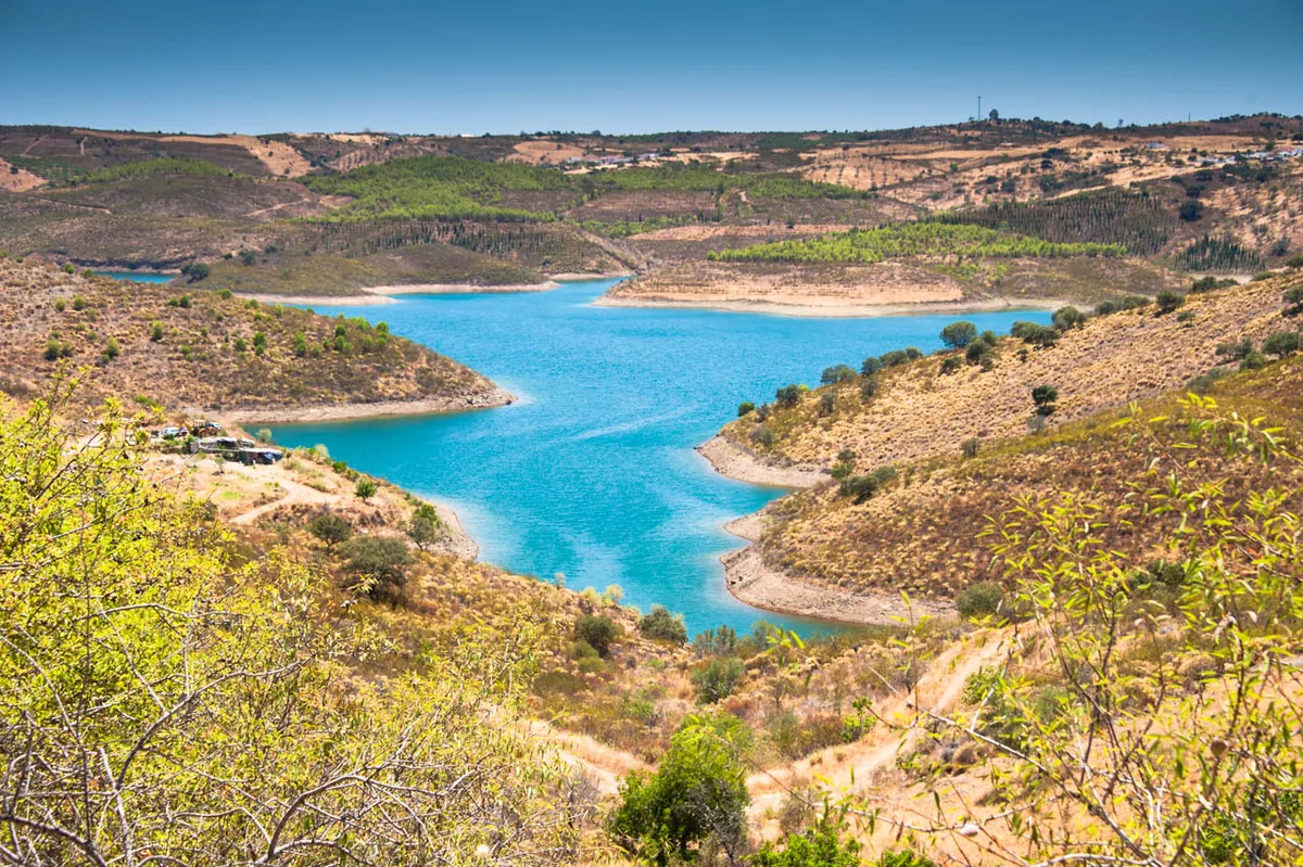 Het turquoise stuwmeer Barragem de Odeleite dat zich door de groene heuvels van het binnenland slingert