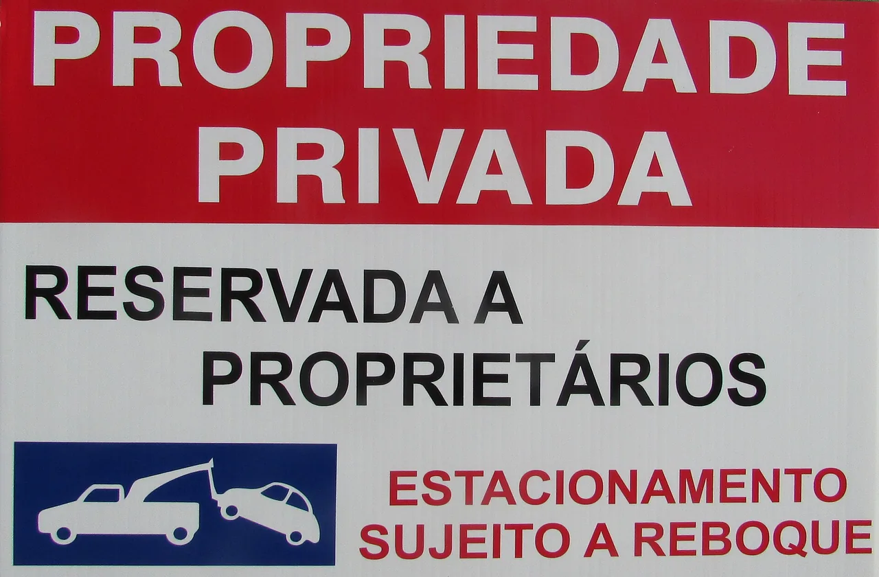 Rood-wit bord met de Portugese tekst 'Propriedade privada, reservada a proprietários, estacionamento sujeito a reboque' en een pictogram van een sleepwagen die een auto meeneemt