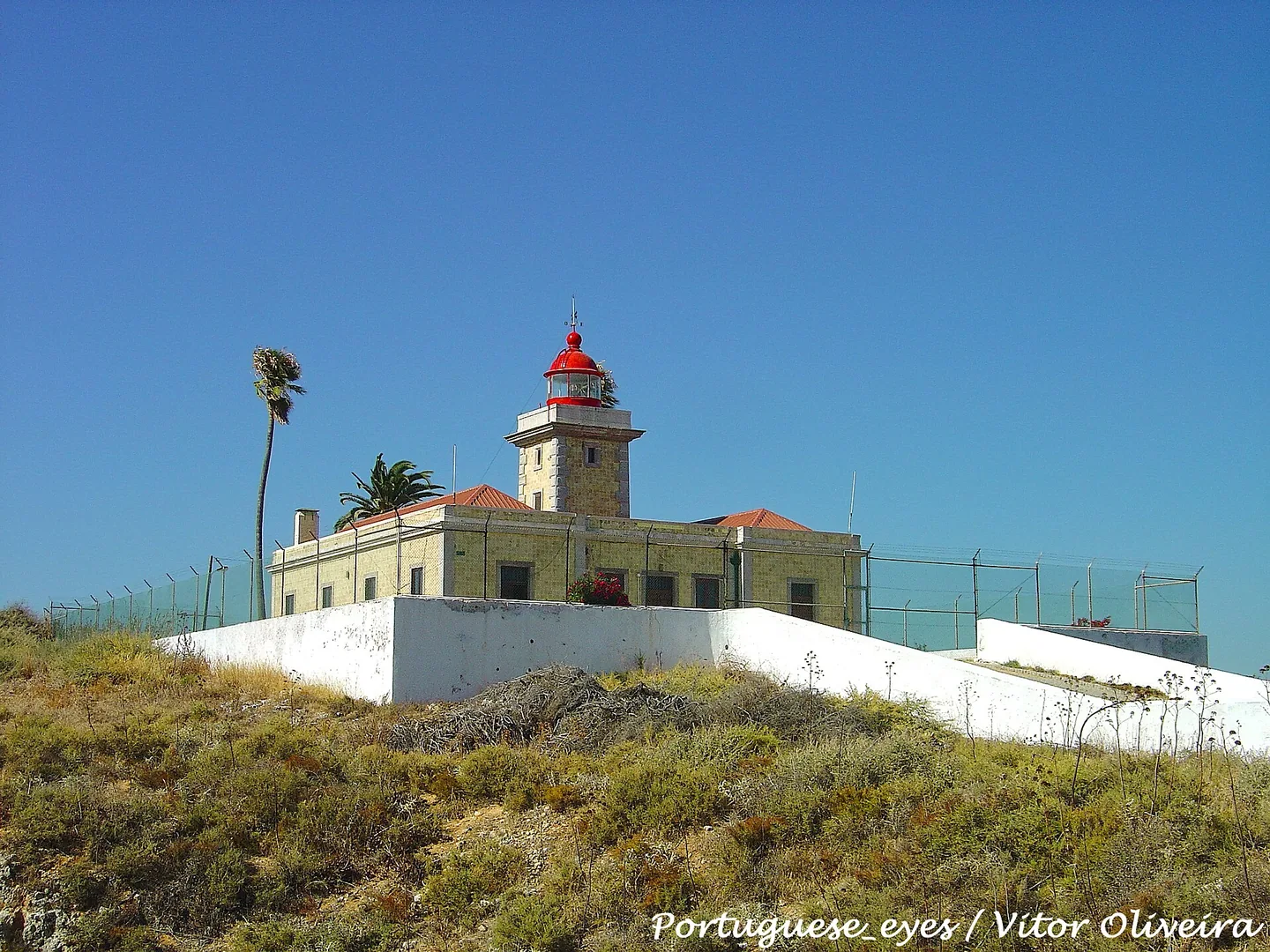 De vuurtoren Farol da Ponta da Piedade met rode koepel op de kaap boven de kliffen