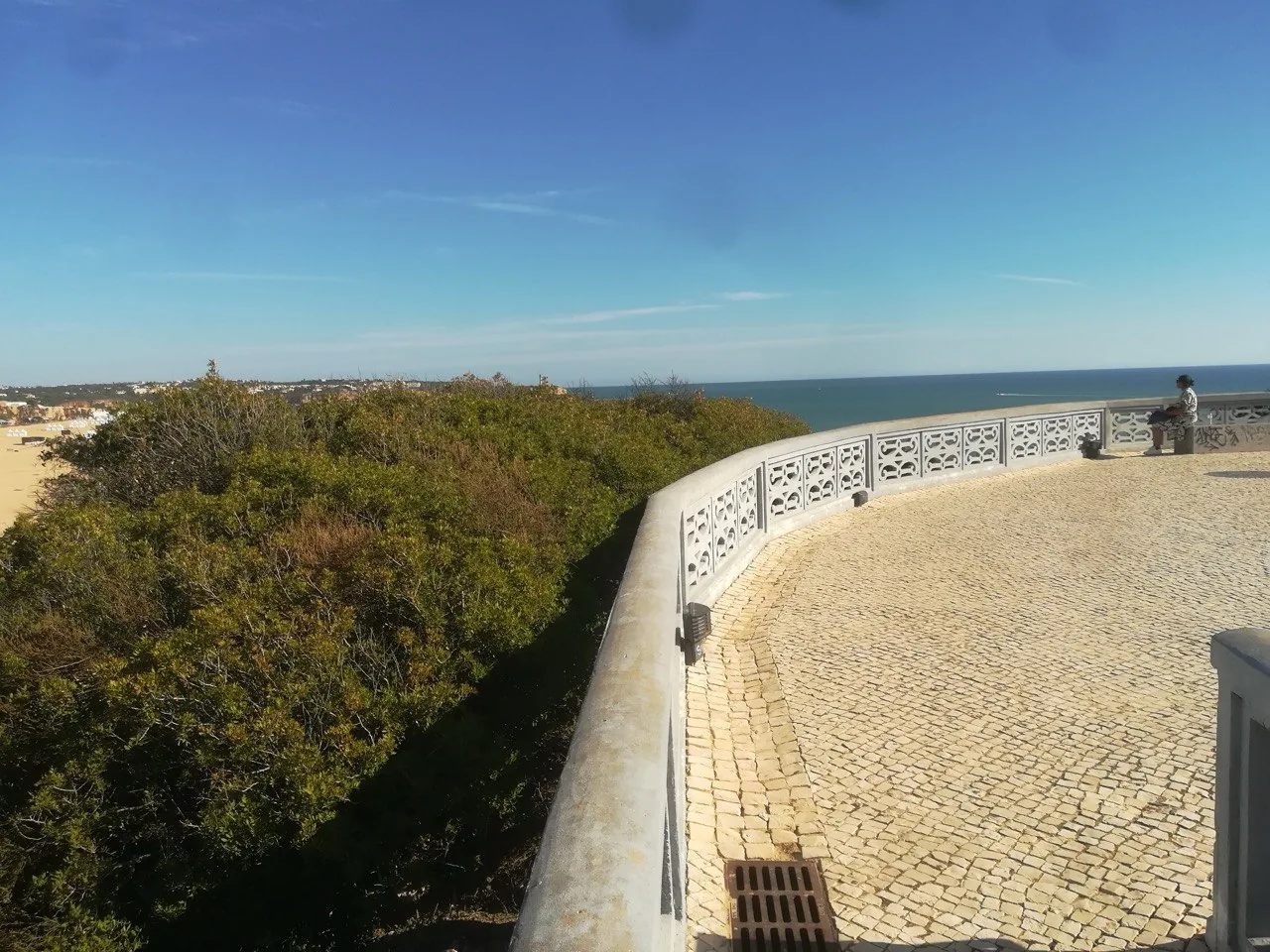 Een uitkijkpunt met een witte balustrade en kasseienpatroon boven de kust bij Portimão