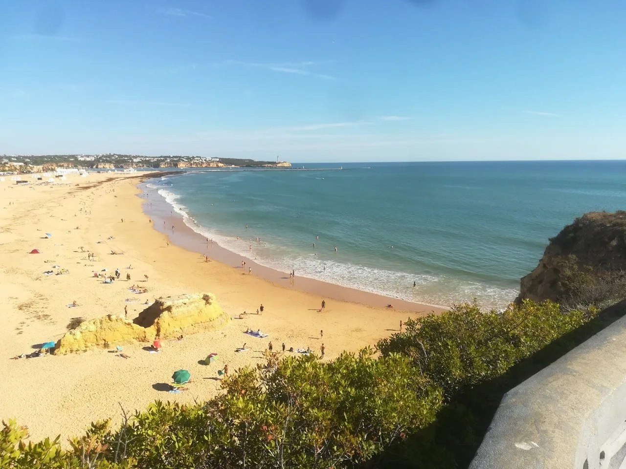 Het brede zandstrand van Praia da Rocha met okerkleurige rotsen en de hoogbouw van Portimão erachter