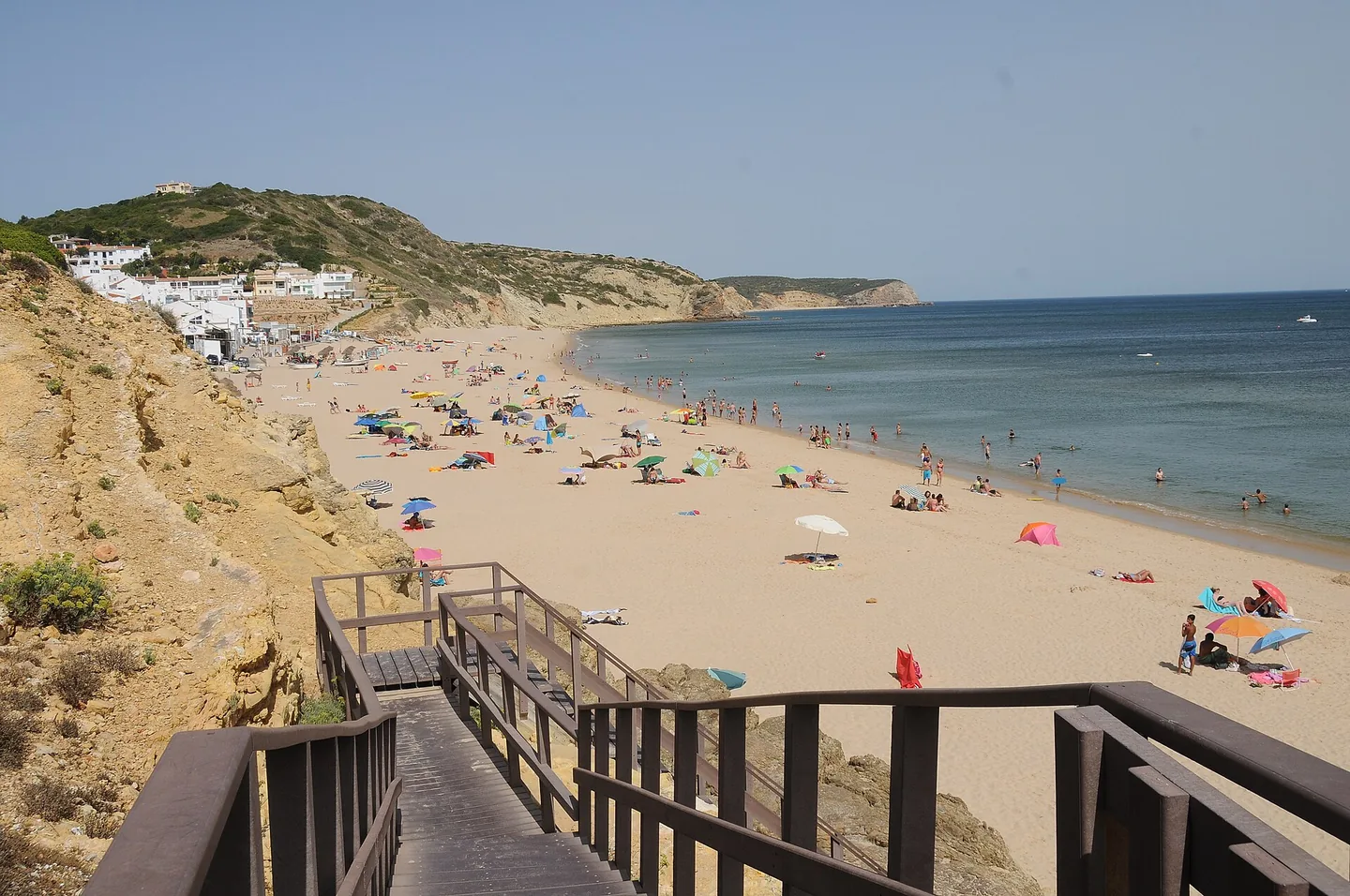 Het Blue Flag-strand van Salema met vissersboten en de okerkleurige kliffen