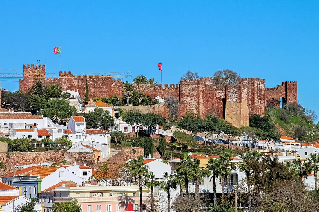 Het rode zandstenen kasteel van Silves boven de witte huizen en palmen van de stad