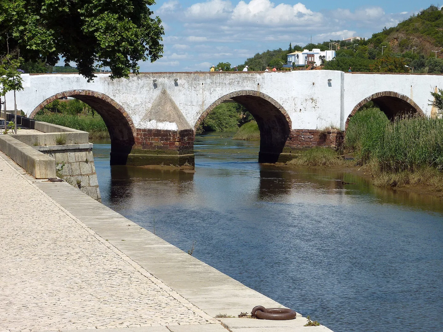 De oude boogbrug over de rivier de Arade aan de voet van Silves, met groene heuvels erachter